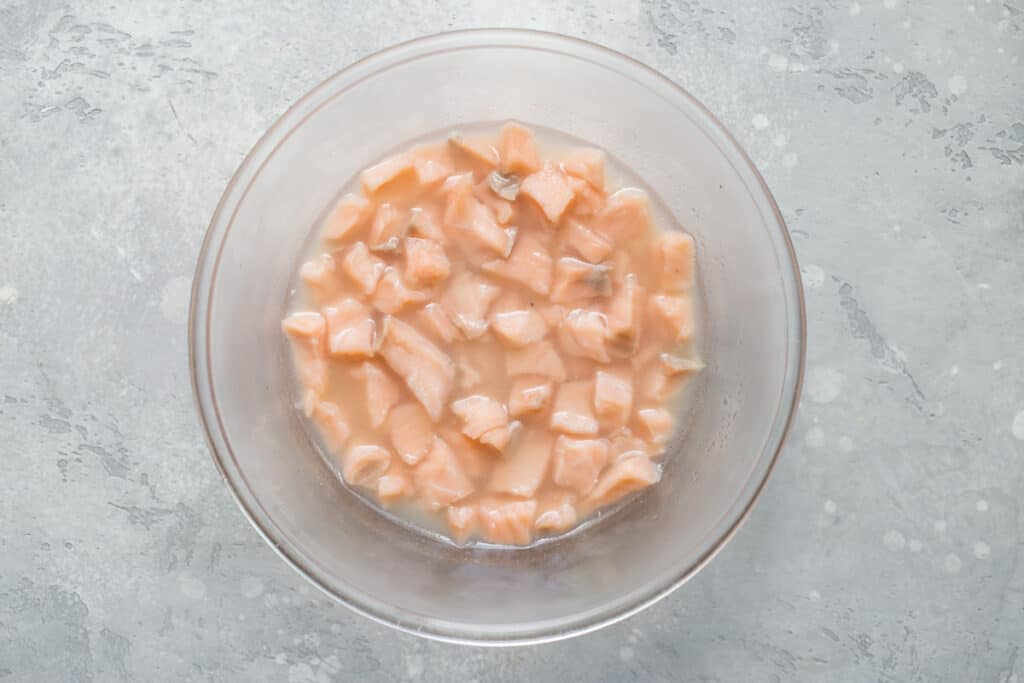 recipiente transparente con salmón en trozos cocido en jugo de cítricos.