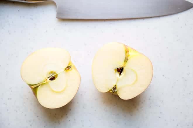 Una manzana partida a la mitad, con semillas