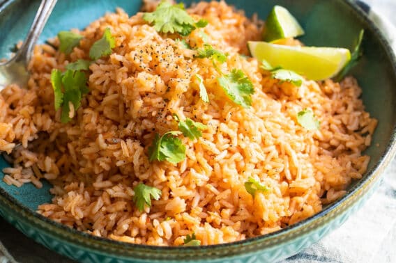 Plato de arroz rojo mexicano adornado con limón y cilantro