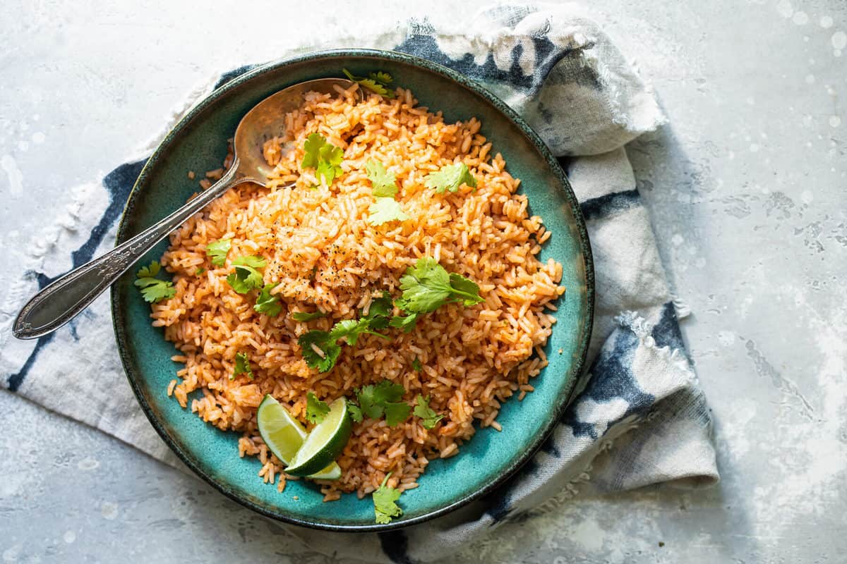 Plato de arroz rojo mexicano adornado con gajos de limón y cilantro