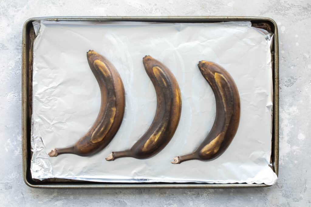 Tre s plátanos maduros sobre una charola con papel para hornear