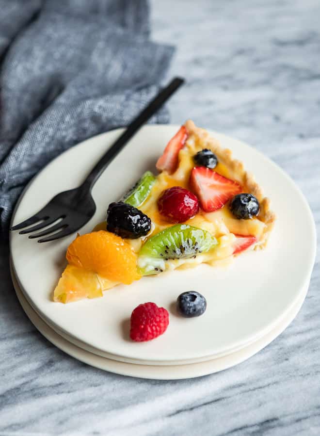 Una rebanada de tarta de frutas frescas servida en un plato blanco