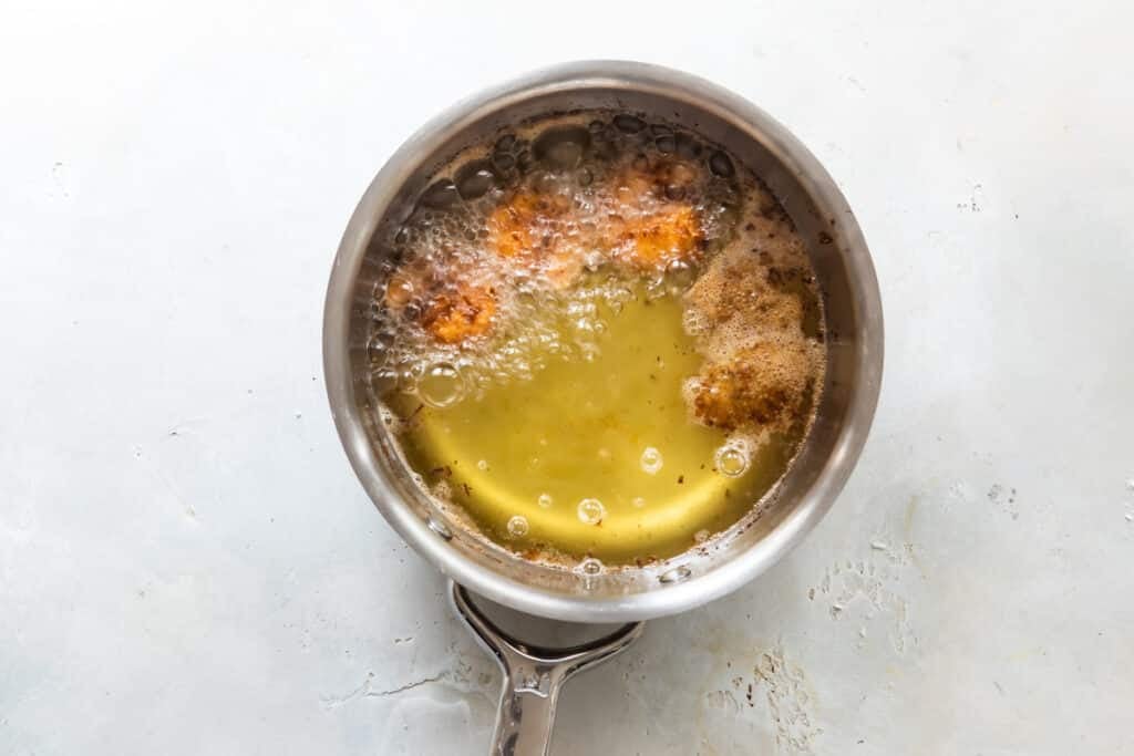 Friendo los camarones previamente empanizados en una olla con aceite caliente 