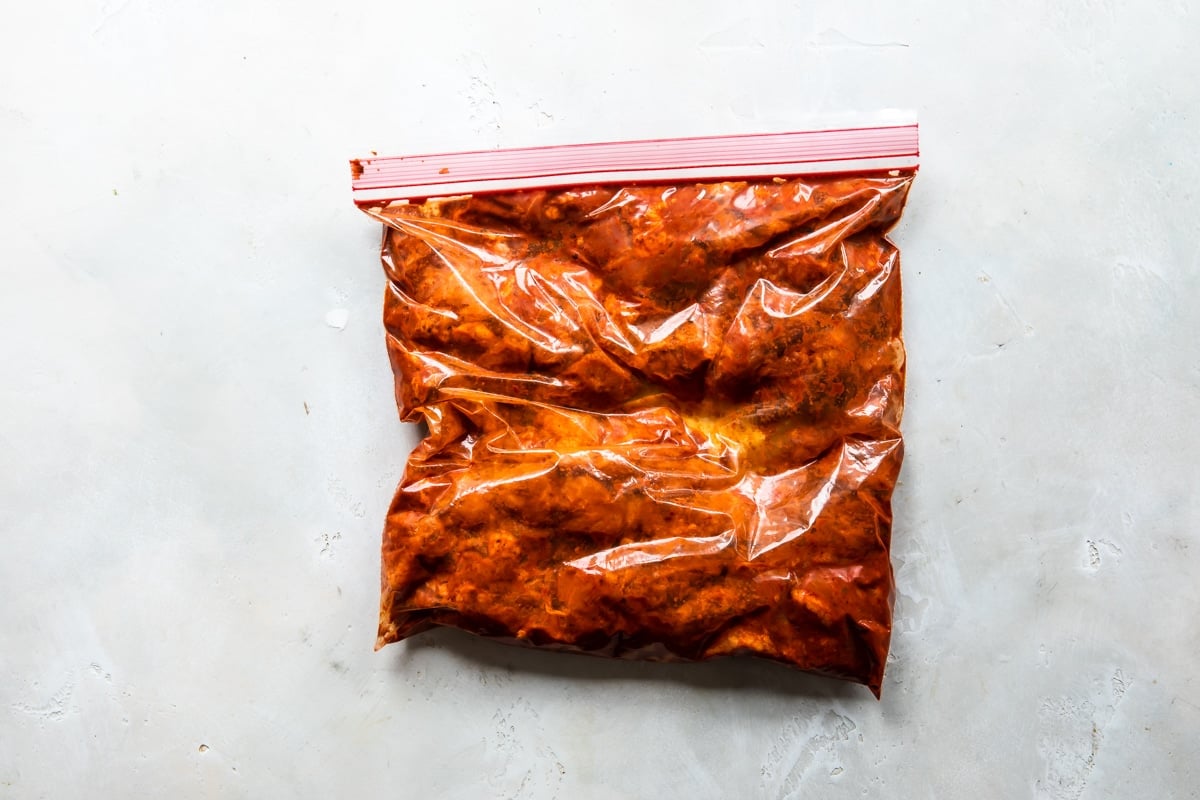 El cerdo se marina en la mezcla de chile y especias en una bolsa de plástico resellable