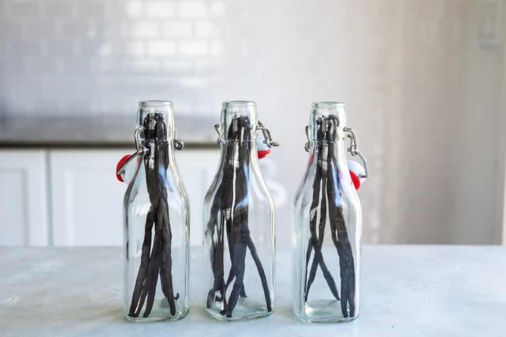 Tres botellas de vidrio con vainas de vainilla enteras