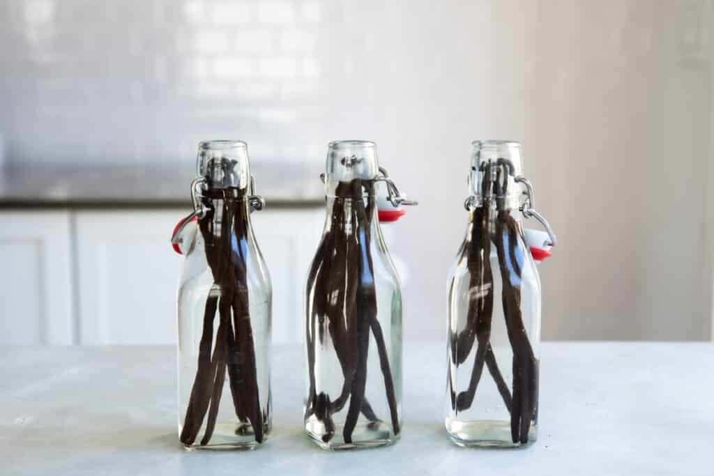 Tres botellas de vidrio con vainas de vainilla enteras y llenas de vodka