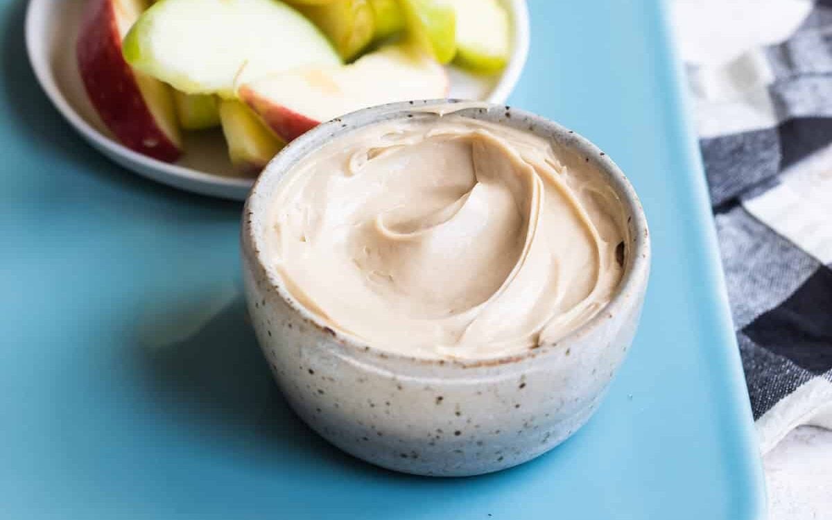 Dip servido en un plato hondo pequeño y un plato con rebanadas de manzana para sumergir en el dip