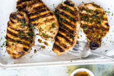 Deliciosas chuletas de cerdo a la parrilla listas para comer, servidas con perejil fresco y un poco de miel por un lado