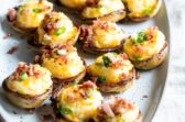 Platón con mini papas rellenas al horno, acompañadas con tocino frito espolvoreado y cebollín picado.