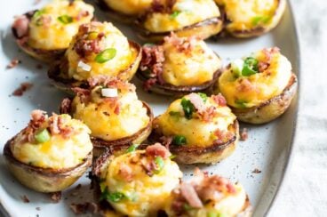 Platón con mini papas rellenas al horno, acompañadas con tocino frito espolvoreado y cebollín picado.
