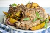 Chuletas de cerdo al horno servidas con papas con cebolla y salvia fresca
